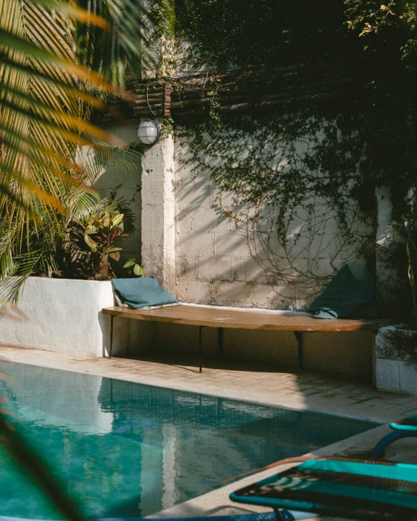 Hiking Telica Volcano in Nicaragua: A Magical Sunrise 20 A tranquil pool area at Coco Calala, Leon, with sunlight filtering through tropical foliage, highlighting the blue waters and wooden pool bench.