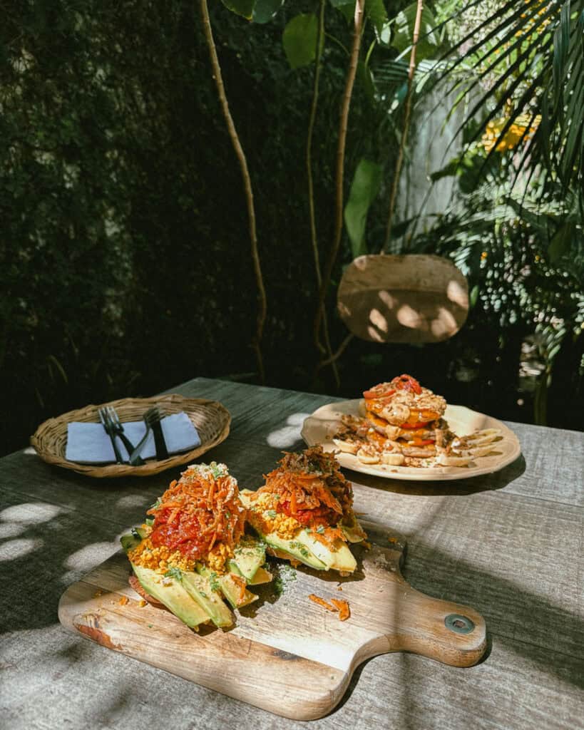 Leon, Nicaragua Travel Guide: The City of Revolution 26 A cozy outdoor dining setup at Coco Calala restaurant in León, featuring artistic plates of avocado toast topped with vibrant garnishes.