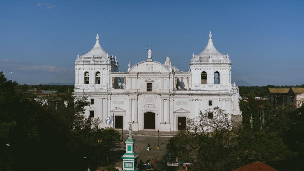18 Best Things to Do in Leon, Nicaragua 18 Panoramic view of the León Cathedral, highlighting the cityscape with volcanoes in the distance under a bright blue sky, seen from the rooftop of the Revolution Museum.