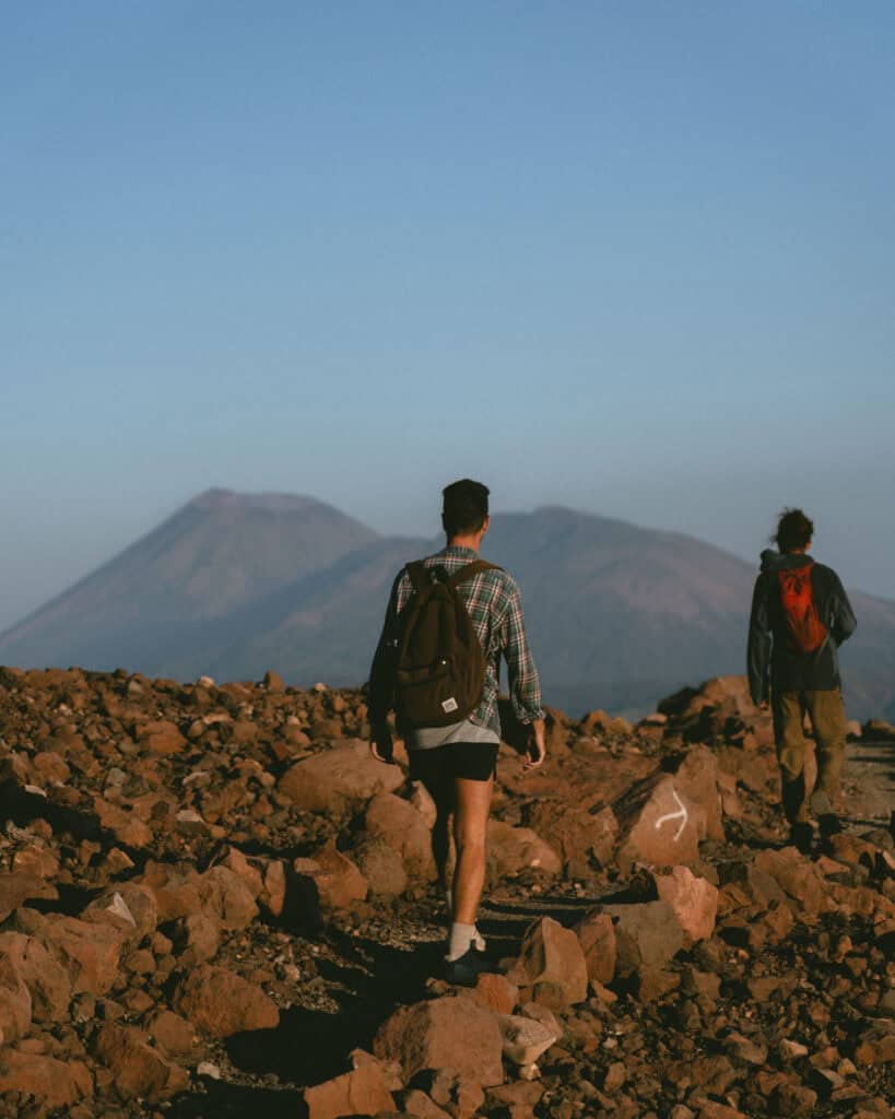 Hiking Telica Volcano in Nicaragua: A Magical Sunrise 15 Brayden walking along a rocky path at Telica Volcano in León, Nicaragua, with distant volcanic peaks visible under a clear blue sky.