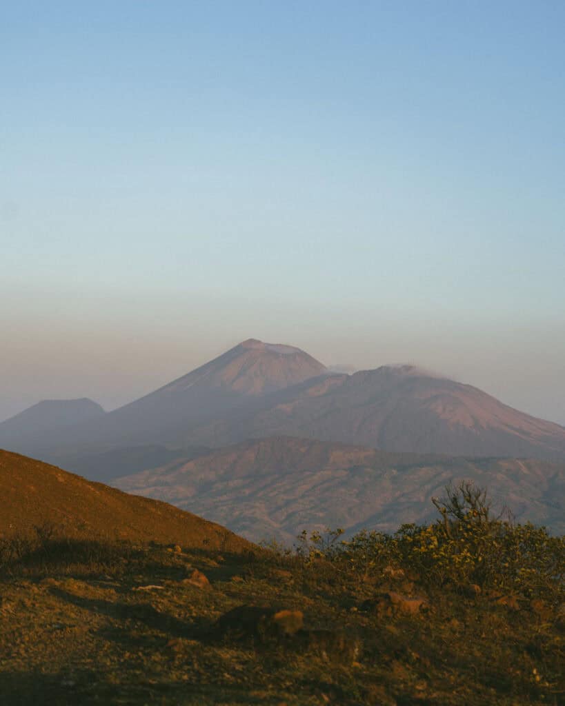 Hiking Telica Volcano in Nicaragua: A Magical Sunrise 14 Distant volcanic peaks under the soft glow of the early morning sun, with light mist rising from the craters.