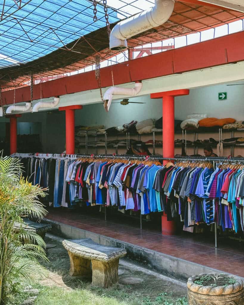18 Best Things to Do in Leon, Nicaragua 30 An open-air thrift shop in León, Nicaragua, with rows of colorful clothes on racks and a rustic interior with potted plants.