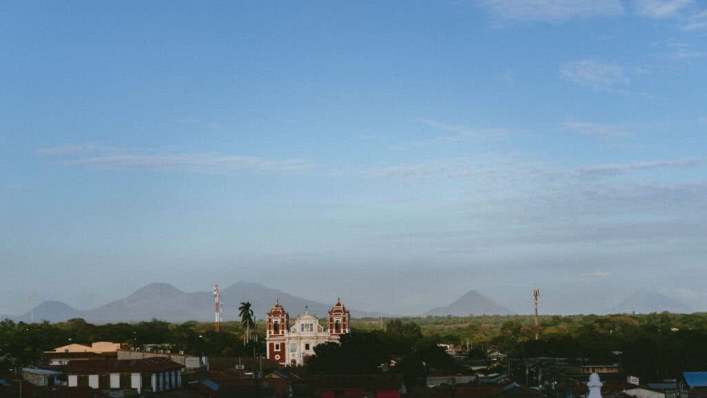 18 Best Things to Do in Leon, Nicaragua 37 Scenic landscape in León, featuring multiple volcanoes on the horizon behind the city, under a wide expanse of clear blue sky.