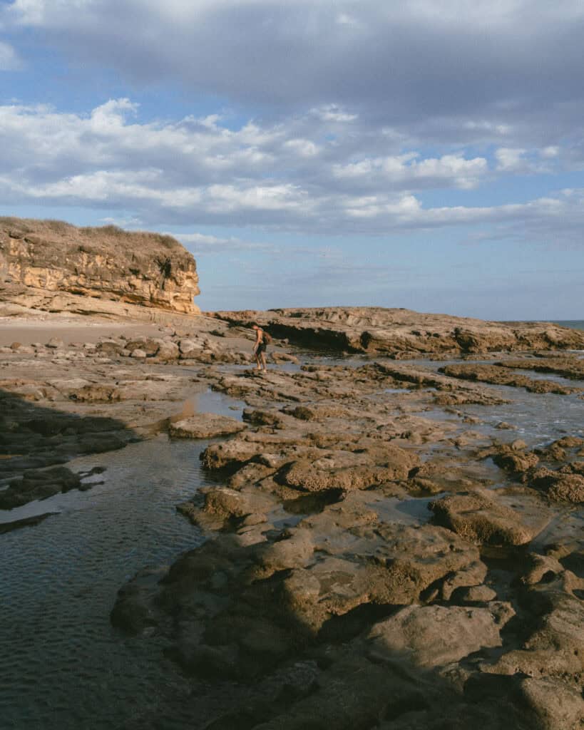 Popoyo, Nicaragua Travel Guide: Surf, Sand and Sunsets 22 Brayden standing on rocky terrain near tidal pools in Guasacate, with the ocean in the background, Popoyo, Nicaragua.