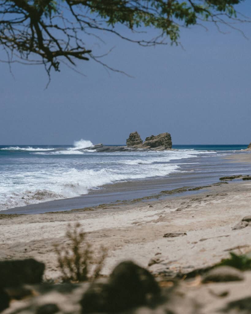 Popoyo, Nicaragua Travel Guide: Surf, Sand and Sunsets 2 A scenic view of Magnific Rock with waves crashing against the rocky shoreline in Popoyo, Nicaragua.