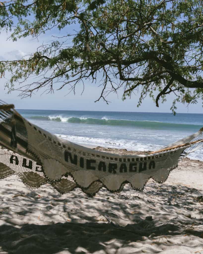Nicaragua Travel Guide: Land of Lakes and Volcanoes 9 A crochet hammock with "Nicaragua" written on it, swaying under a tree with a view of waves on Playa Popoyo.