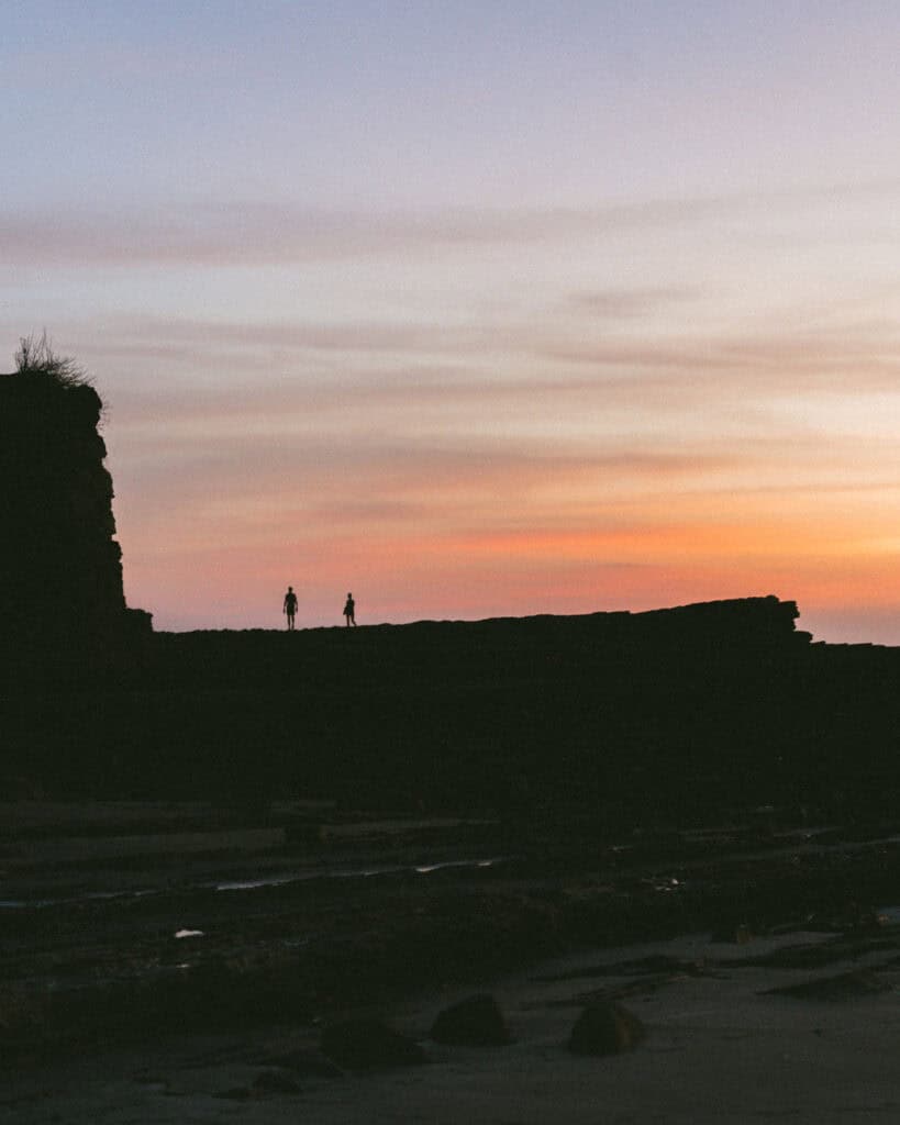 Popoyo, Nicaragua Travel Guide: Surf, Sand and Sunsets 20 Silhouettes of two figures standing on the 'Magnific Rock' against a vivid sunset in Popoyo, Nicaragua.
