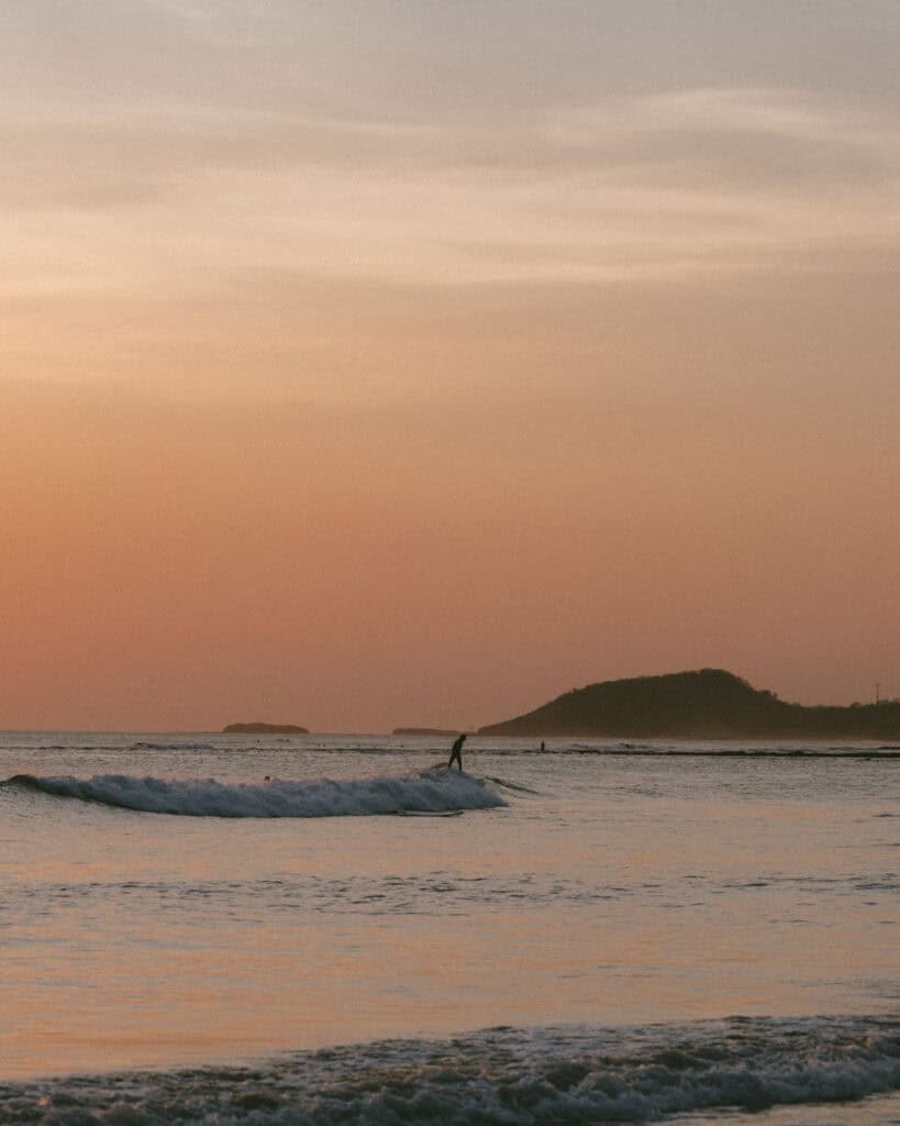 Nicaragua Travel Guide: Land of Lakes and Volcanoes 6 A closer view of surfers enjoying the waves at sunset, with vibrant orange hues reflecting off the water at Popoyo.