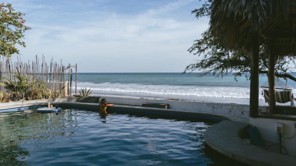Popoyo, Nicaragua Travel Guide: Surf, Sand and Sunsets 14 Sally leaning on the edge of the infinity pool with a view of the ocean horizon, surrounded by tropical plants and a peaceful ambiance at Waves and Dreams, Popoyo.