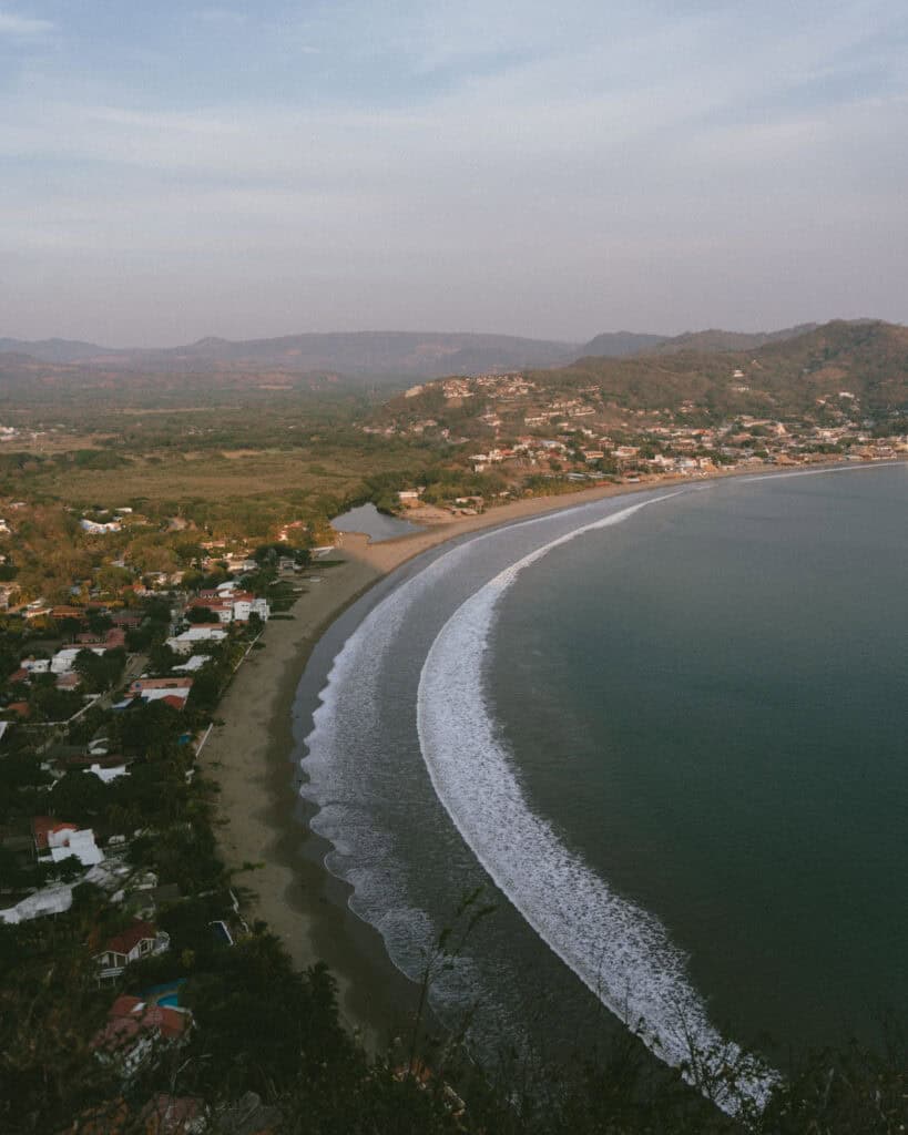 Nicaragua Travel Guide: Land of Lakes and Volcanoes 17 A sweeping view of San Juan del Sur Bay from the Cristo de La Divina Misericordia viewpoint, with the shoreline curving around the calm waters.