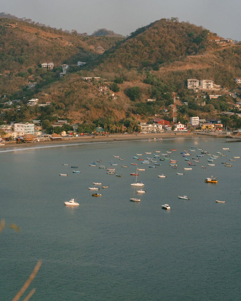 San Juan del Sur, Nicaragua Travel Guide: Worth the Hype? 28 A scenic vista showing boats anchored in San Juan del Sur Bay, surrounded by rolling hills and coastal houses.