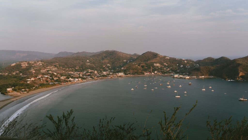 San Juan del Sur, Nicaragua Travel Guide: Worth the Hype? 20 A panoramic shot of San Juan del Sur Bay, capturing the expansive coastline and the cluster of boats on the serene waters, seen from the Cristo statue.