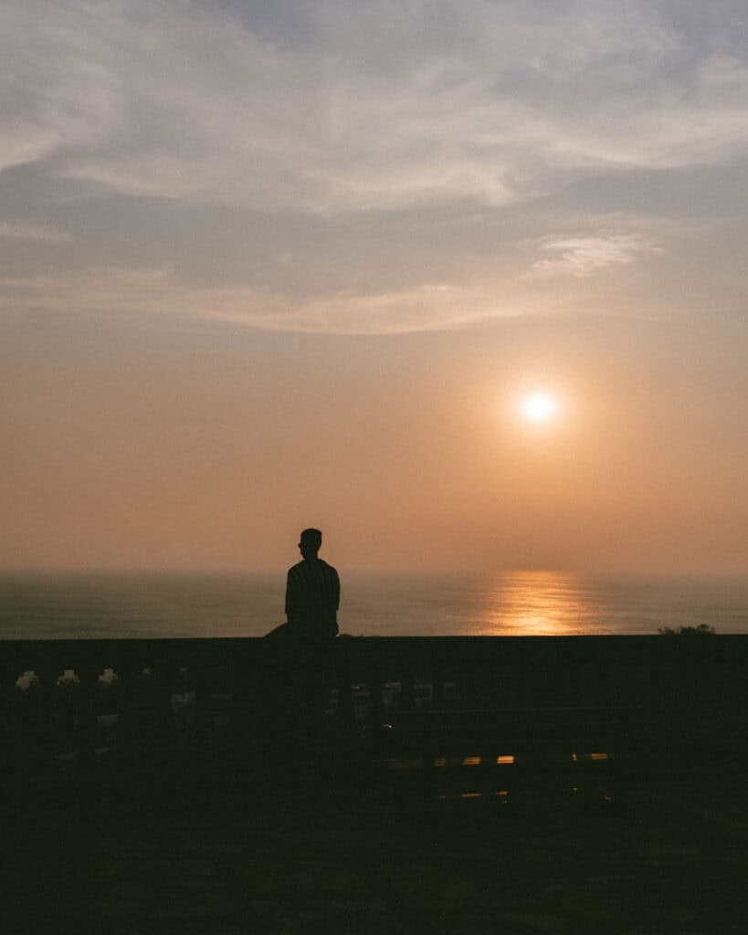 San Juan del Sur, Nicaragua Travel Guide: Worth the Hype? 19 Brayden silhouetted against a glowing sunset at the Cristo de La Divina Misericordia, with the ocean reflecting the warm hues of the setting sun.