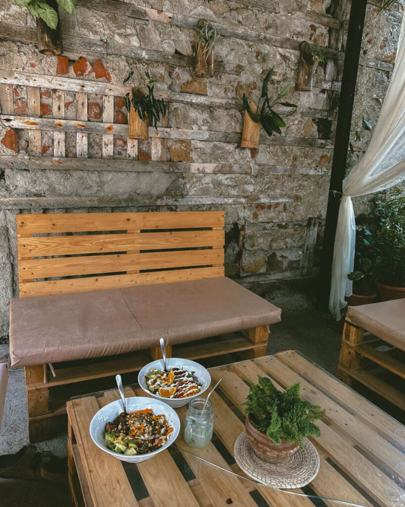 San Juan del Sur, Nicaragua Travel Guide: Worth the Hype? 34 A peaceful corner at Olha restaurant in San Juan del Sur, with cozy bench seating and greenery against a stone wall backdrop.