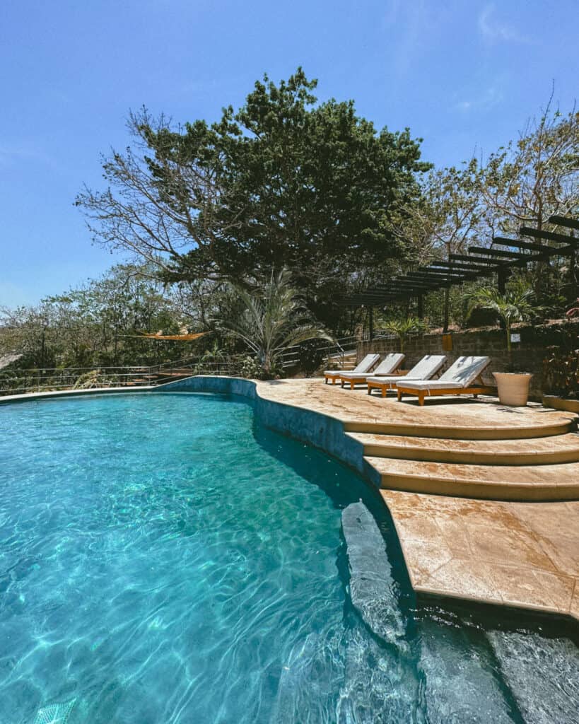 San Juan del Sur, Nicaragua Travel Guide: Worth the Hype? 24 The pool at TreeCasa Resort in San Juan del Sur, surrounded by sun loungers and tropical greenery under a clear blue sky.