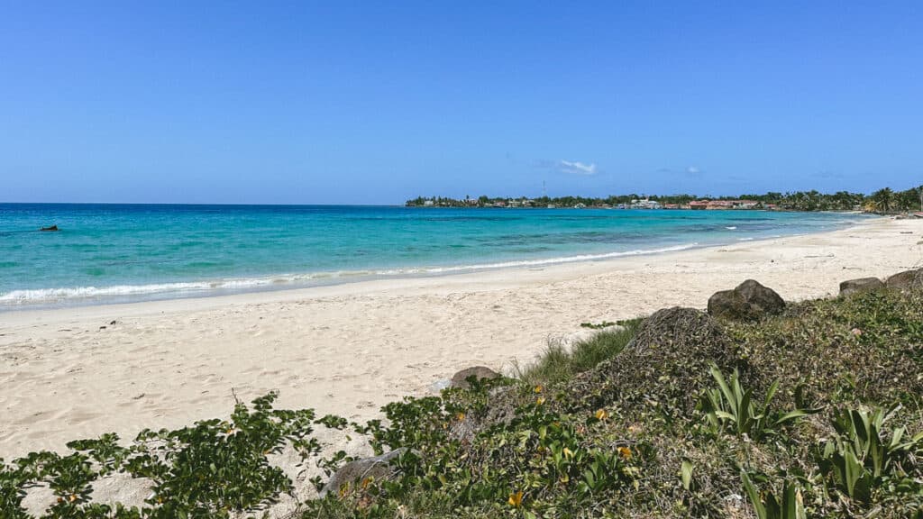 Big Corn Island, Nicaragua: The Underrated Corn Island 22 A landscape photo of Playa Coco on Big Corn Island with calm, bright turquoise waters, white sand and greenery in the foreground.