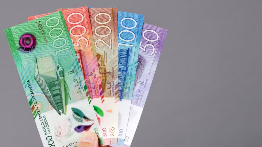Our Nicaragua Travel Cost: Is Nicaragua Cheap? 1 A hand holding up a spread out wad of Nicaraguan Cordoba notes, with 1,000 (green), 500 (red), 200 (orange), 100 (blue) and 50 (purple).