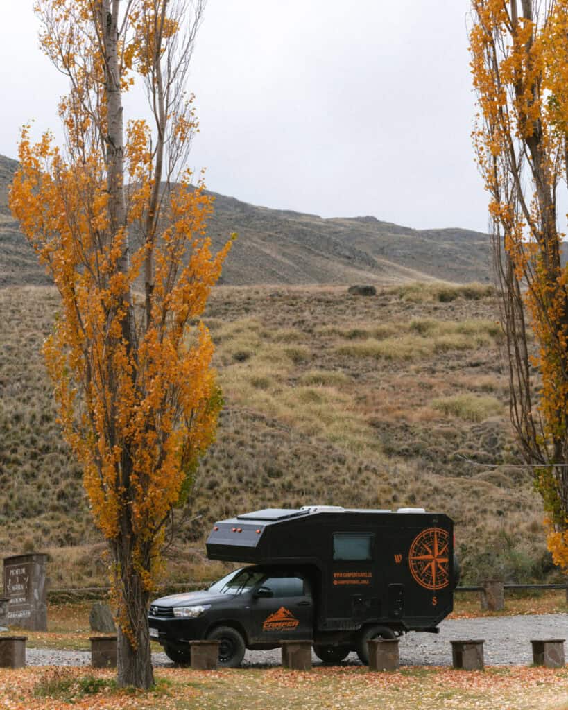Valle Chacabuco Sector Guide: Parque Nacional Patagonia, Chile 43 A black camper van is parked between two golden autumn trees, set against a backdrop of rolling hills in Patagonia