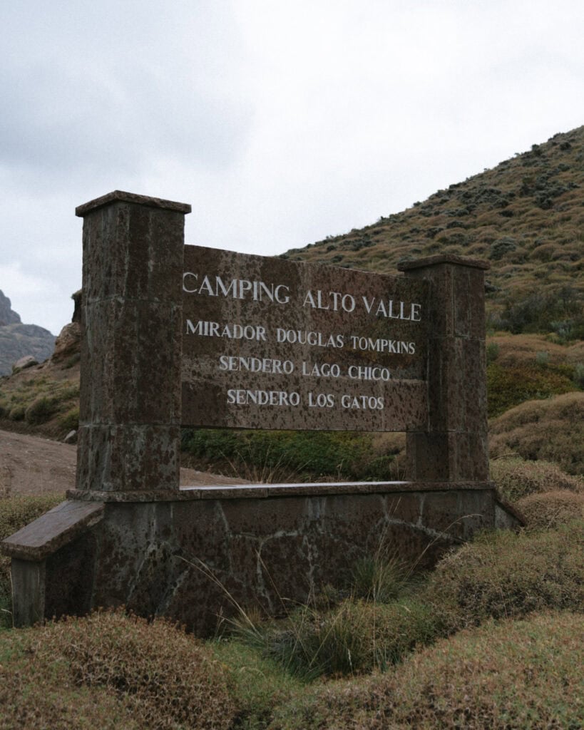 Valle Chacabuco Sector Guide: Parque Nacional Patagonia, Chile 27 A stone sign marks the entrance to Camping Alto Valle and nearby hiking trails, with dry hills and overcast skies in the background