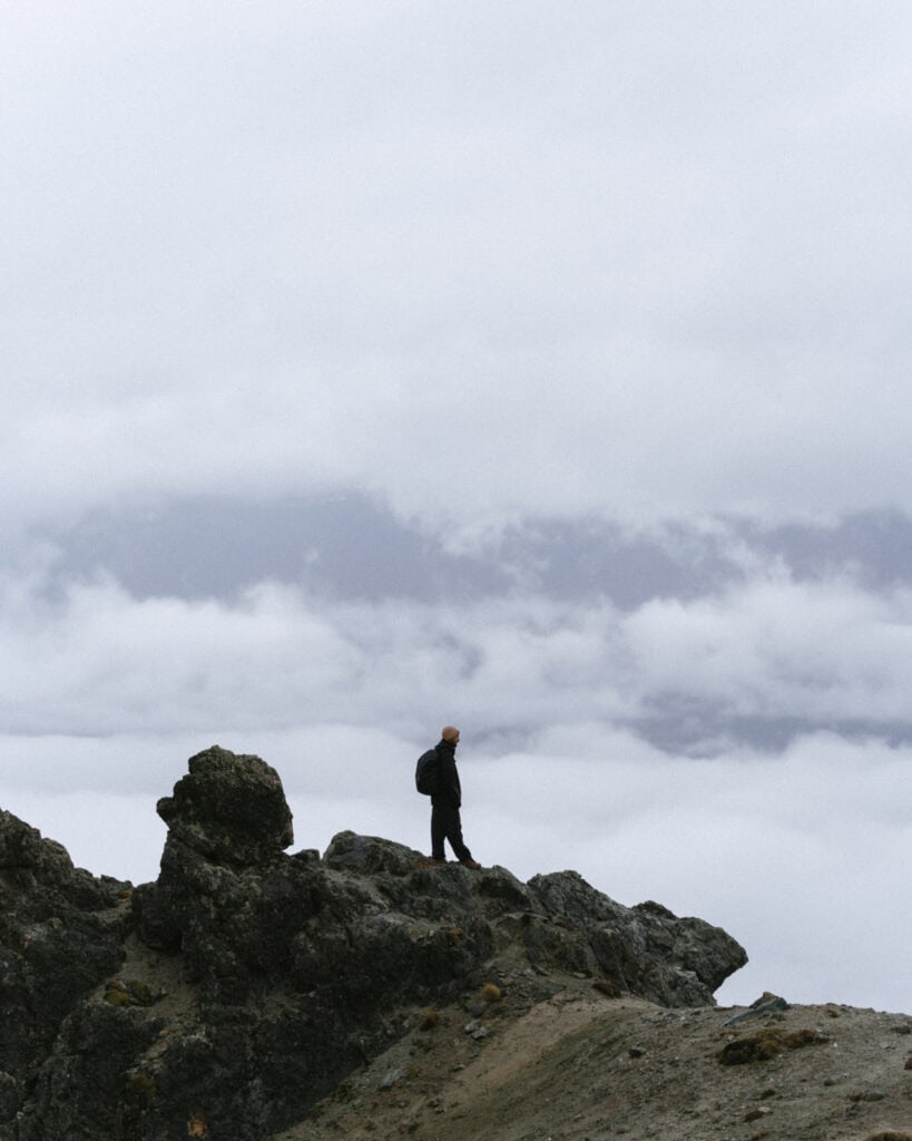 Valle Chacabuco Sector Guide: Parque Nacional Patagonia, Chile 1 Brayden stands confidently on a rugged, rocky peak with his backpack, gazing out over a cloudy horizon in Parque Nacional Patagonia