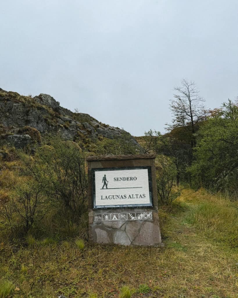 Valle Chacabuco Sector Guide: Parque Nacional Patagonia, Chile 34 Stone trail marker for Sendero Lagunas Altas surrounded by green shrubs and rocky hillsides under an overcast sky in Parque Nacional Patagonia