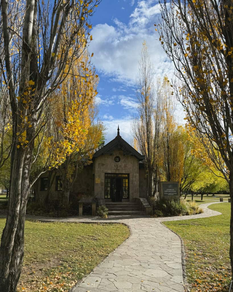 Our Epic 3-Week Carretera Austral Road Trip Itinerary 23 Stone building of the park’s visitor center nestled among golden-leaved trees and accessed by a paved pathway under a blue sky