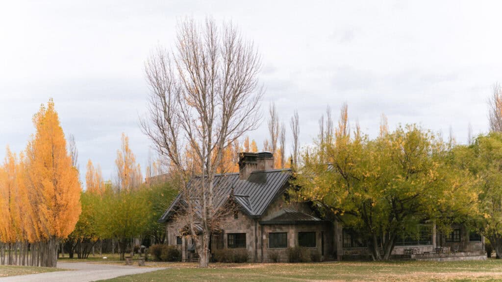 Valle Chacabuco Sector Guide: Parque Nacional Patagonia, Chile 18 Autumn-colored trees surround a rustic stone building under cloudy skies, capturing the welcoming landscape of the Patagonia park headquarters