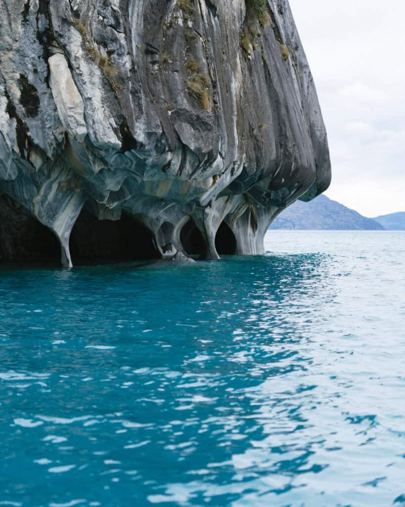 How to Visit the Marble Caves in Chile: Worth the Journey? 5 Dramatic marble formations rise like cathedral pillars from the lake at Capillas de Mármol, Puerto Río Tranquilo, Chile, with deep blue water below and rugged cliffs above
