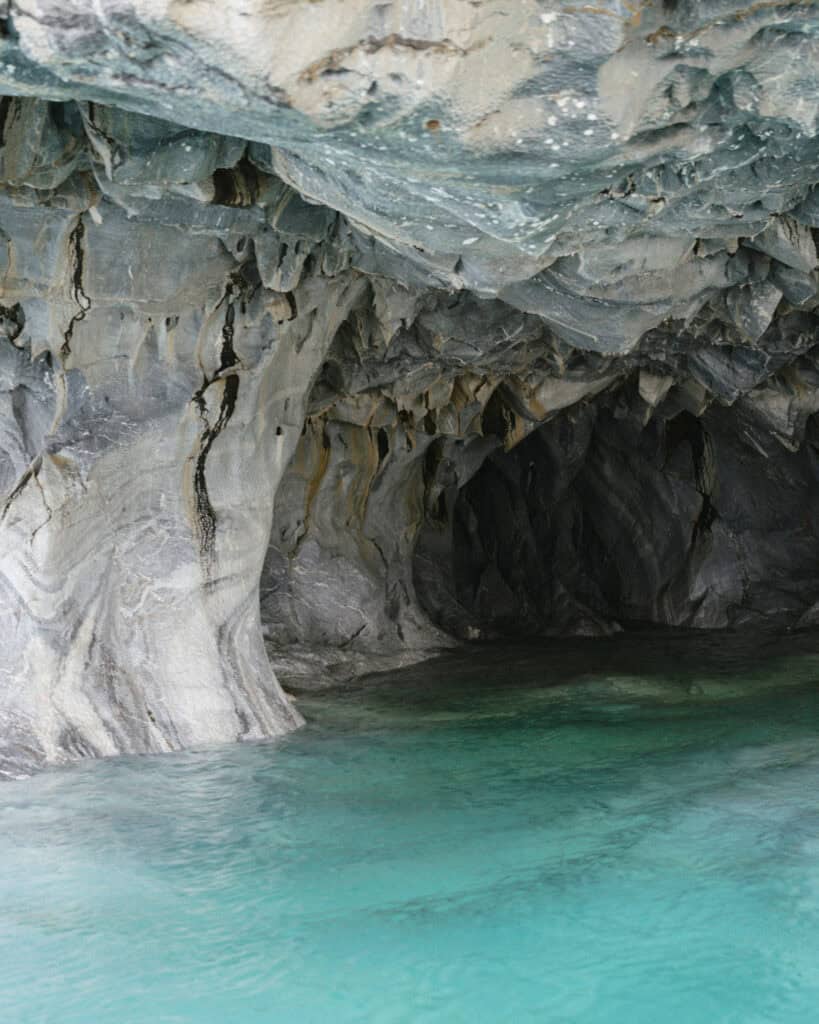 How to Visit the Marble Caves in Chile: Worth the Journey? 14 Interior view of a marble cave with jagged walls and turquoise blue water at Capillas de Mármol in Puerto Río Tranquilo, Chile, capturing the surreal beauty of this natural wonder