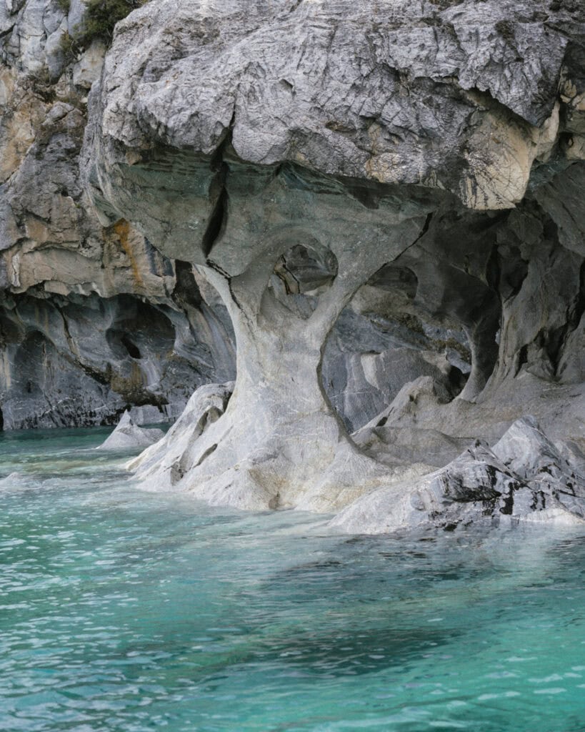 How to Visit the Marble Caves in Chile: Worth the Journey? 32 A uniquely shaped marble formation resembling a column supports a rocky overhang above the clear teal waters at Capillas de Mármol, near Puerto Río Tranquilo, Chile