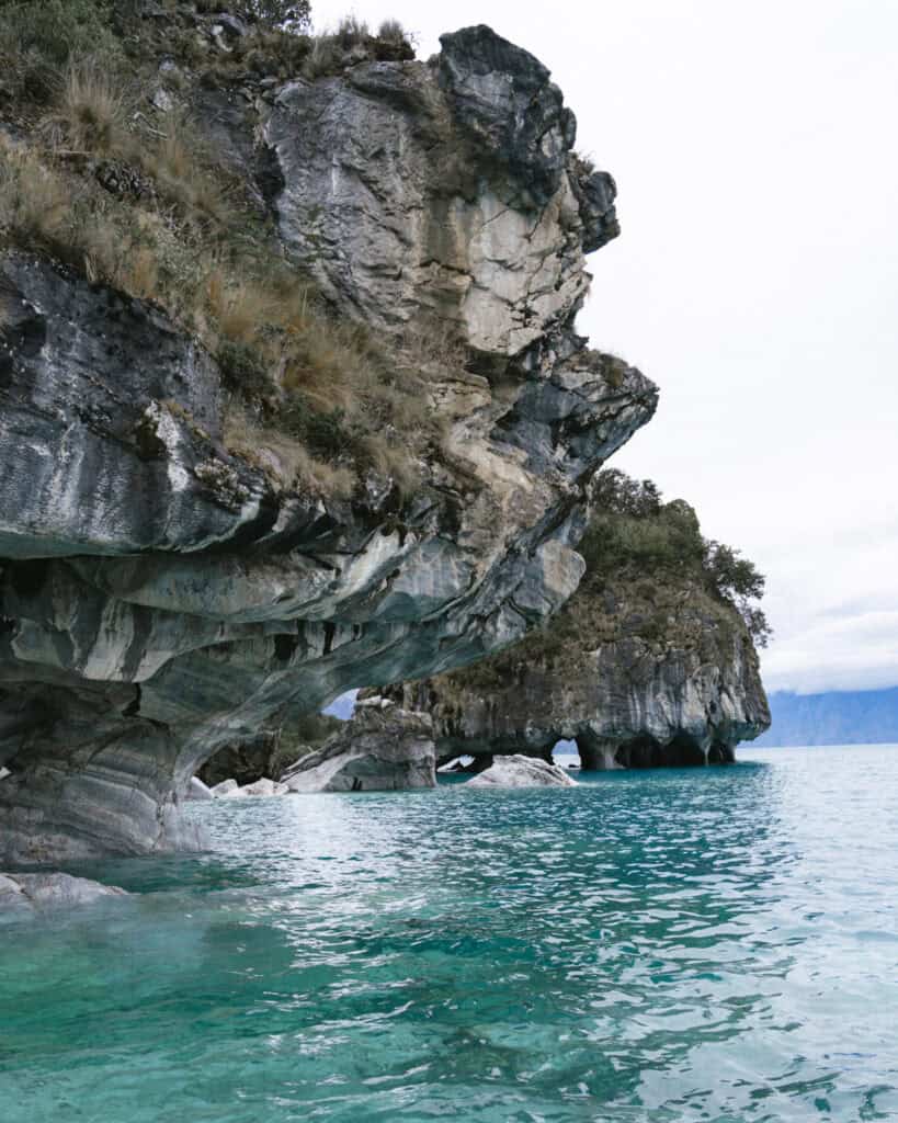How to Visit the Marble Caves in Chile: Worth the Journey? 25 Curved marble cliffs with textured rock formations hover above the clear, aquamarine waters at Capillas de Mármol near Puerto Río Tranquilo, Chile
