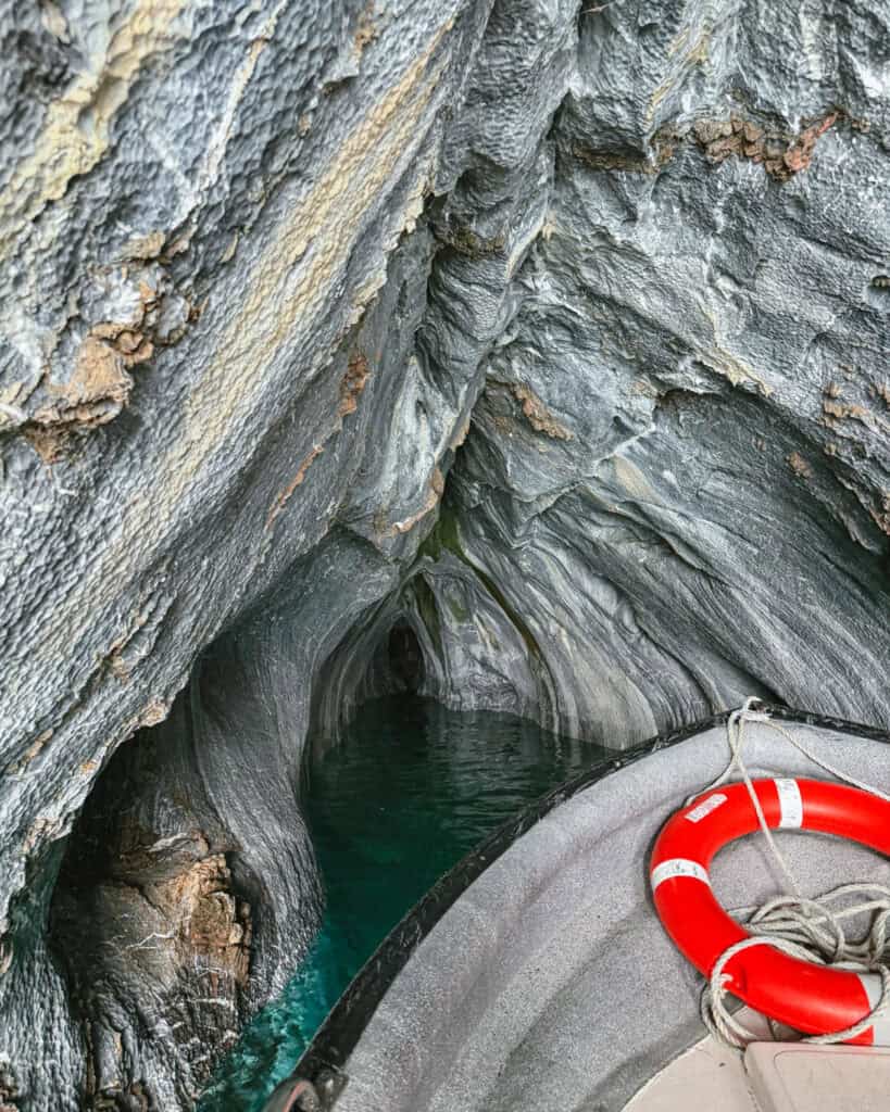 How to Visit the Marble Caves in Chile: Worth the Journey? 26 The bow of a boat floats inside a narrow marble cave in Puerto Río Tranquilo, Chile, where striped stone walls meet clear emerald water