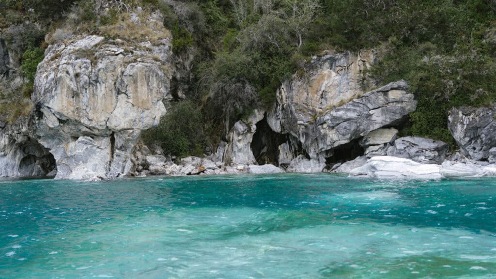 How to Visit the Marble Caves in Chile: Worth the Journey? 28 A wide shot of a large marble rock formation known as the Capillas de Marmol rising from General Carrera Lake in Puerto Río Tranquilo, with clear blue waters and a forested backdrop