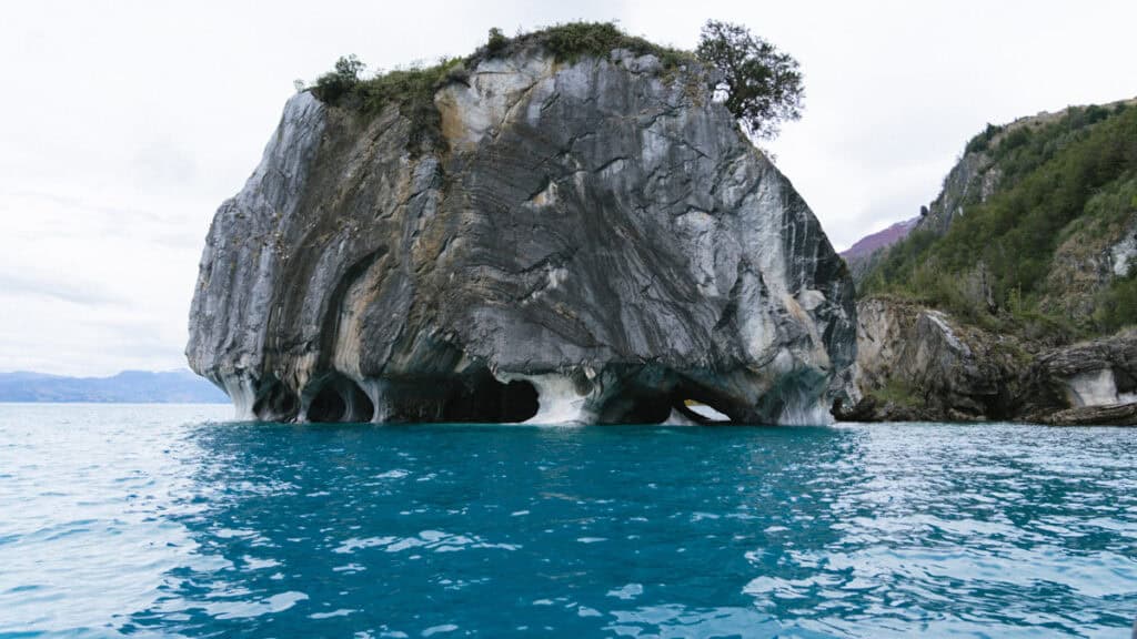 How to Visit the Marble Caves in Chile: Worth the Journey? 13 A wide shot of a large marble rock formation known as the Marble Cathedral rising from General Carrera Lake in Puerto Río Tranquilo, with clear blue waters and a forested backdrop
