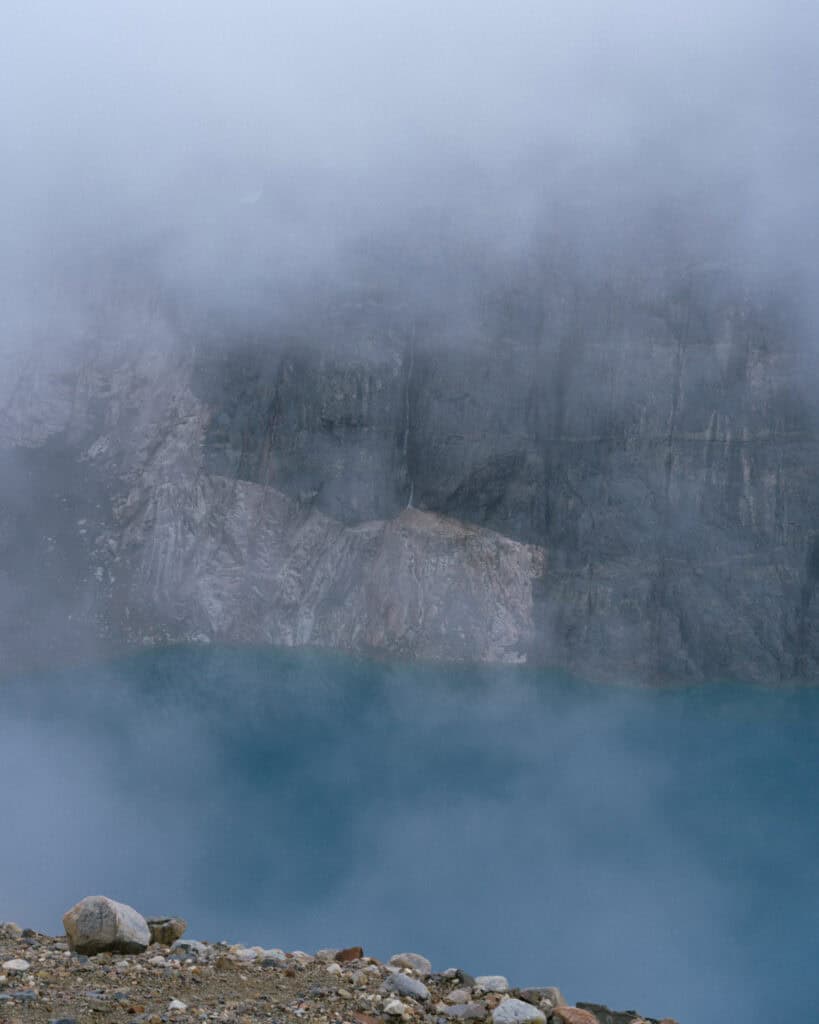 Villa Cerro Castillo, Chile Travel Guide: Hiking & Huemuls 14 A mist-covered turquoise lagoon lies at the base of a steep, rocky cliff in Villa Cerro Castillo National Park, partially hidden by swirling fog