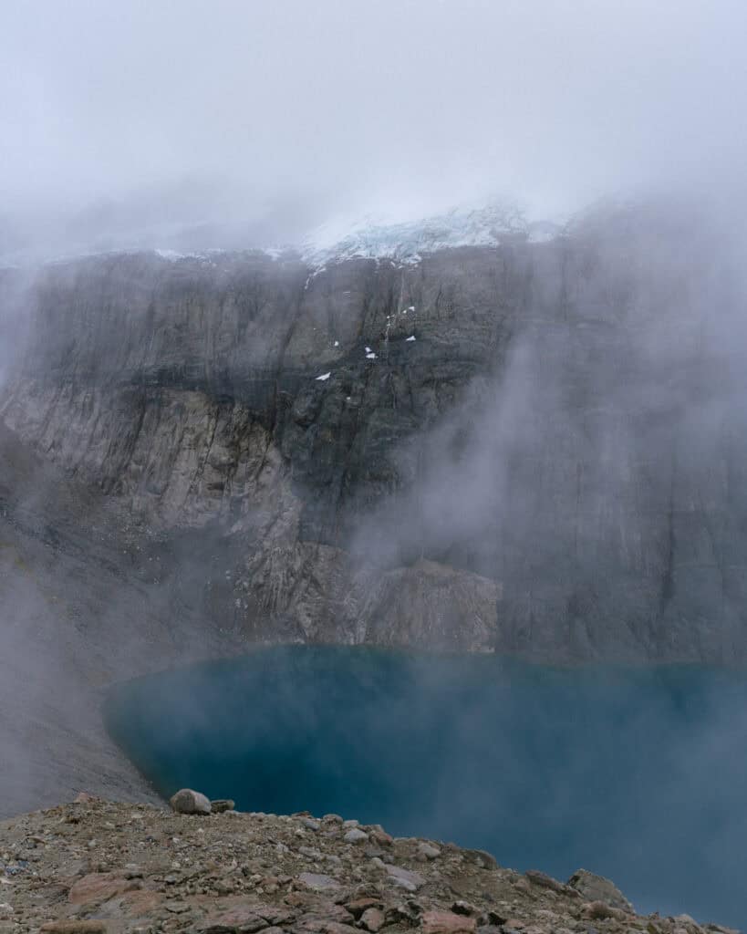 Villa Cerro Castillo, Chile Travel Guide: Hiking & Huemuls 3 A deep blue alpine lagoon rests at the base of steep, rocky walls in Villa Cerro Castillo National Park, with glacier melt visible at the top of the cliffs