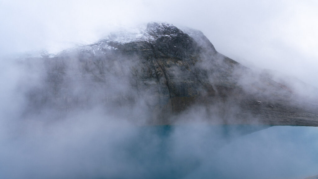 Villa Cerro Castillo, Chile Travel Guide: Hiking & Huemuls 4 Mist rises off a vivid blue lagoon as it laps against the stony shores beneath a towering, snow-speckled peak in Villa Cerro Castillo National Park