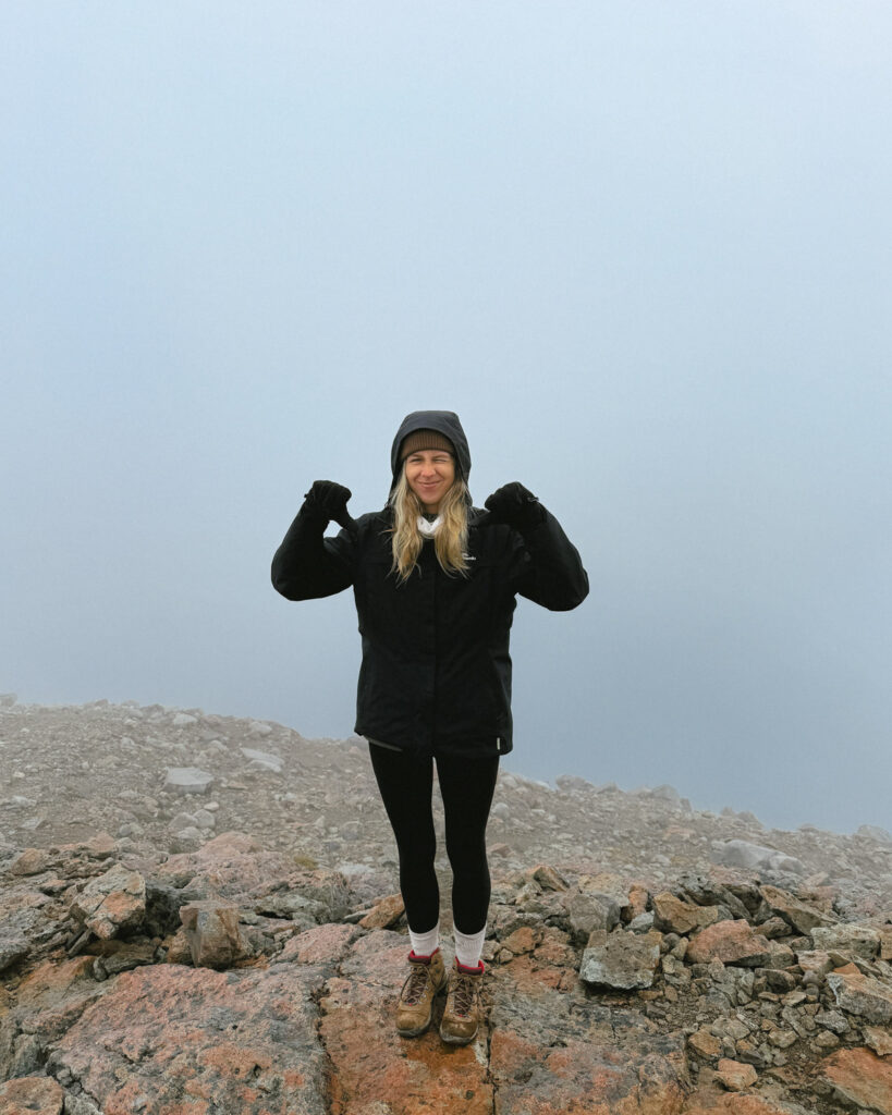 Laguna Cerro Castillo, Chile Hiking Guide 20 Sally stands on rocky terrain at Villa Cerro Castillo National Park, bundled in hiking gear and smiling proudly amid dense fog with barely visible scenery behind her
