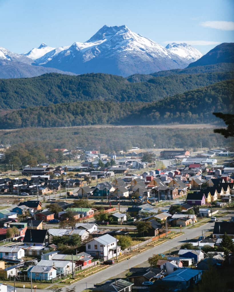 Villa O'Higgins, Chile Guide: End of the Carretera Austral 1 Closer aerial shot of Villa O'Higgins, featuring tidy rows of houses and buildings with the majestic, snow-covered Patagonian peaks and lush green forest in the background