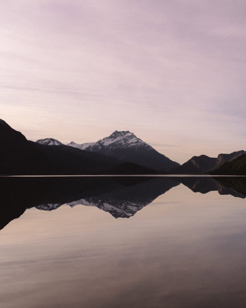 Villa O'Higgins, Chile Guide: End of the Carretera Austral 29 A vertical view of a tranquil scene at Lago Cisnes in Villa O'Higgins, showing the iconic pyramid-shaped mountain mirrored perfectly in the glassy water