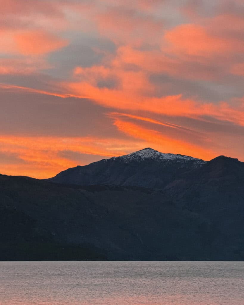 Villa O'Higgins, Chile Guide: End of the Carretera Austral 15 A dramatic mountain silhouette above Lago O’Higgins during sunrise, with glowing pink and orange clouds lighting up the sky