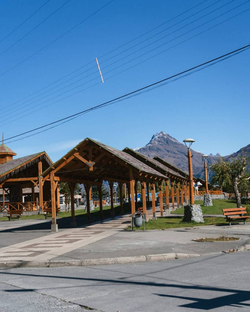 Villa O'Higgins, Chile Guide: End of the Carretera Austral 17 Covered wooden walkways in the town plaza of Villa O’Higgins with a backdrop of a sharp-peaked mountain and blue skies