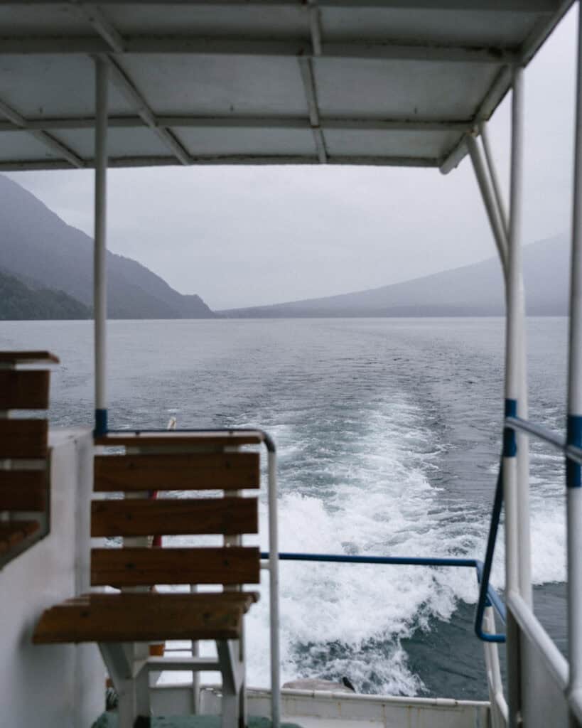 Cruce Andino: The Scenic Route From Chile to Argentina 11 A view from the back of a boat cruising through Lago Todos Los Santos, showing the foamy trail in the water and misty Andes mountains under gray skies