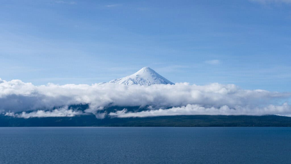 Cruce Andino: The Scenic Route From Chile to Argentina 14 Wide scenic view of Volcán Osorno above Lago Llanquihue with a thick cloud layer near the base, showcasing the natural beauty around Puerto Varas