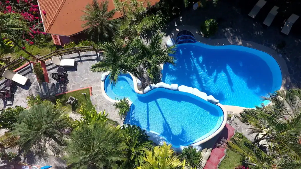 15 Best Things to Do in Montezuma Costa Rica 32 A top down aerial shot of two kidney shaped swimming pools surrounded by palm trees at Hotel El Jardin in Montezuma Costa Rica.