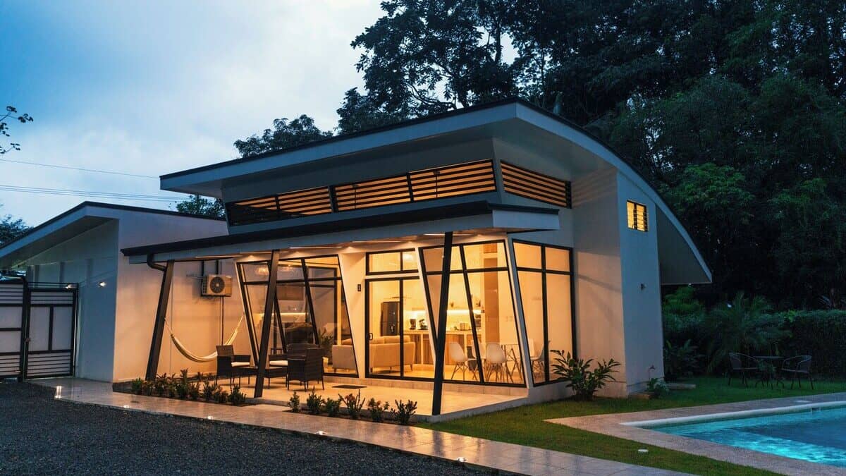 18 Wonderful Things to Do in Uvita Costa Rica 33 A small white house set amongst the forest lit up at night at Tamandua Homes in Uvita. There is a pool just in sight to the right of the image.