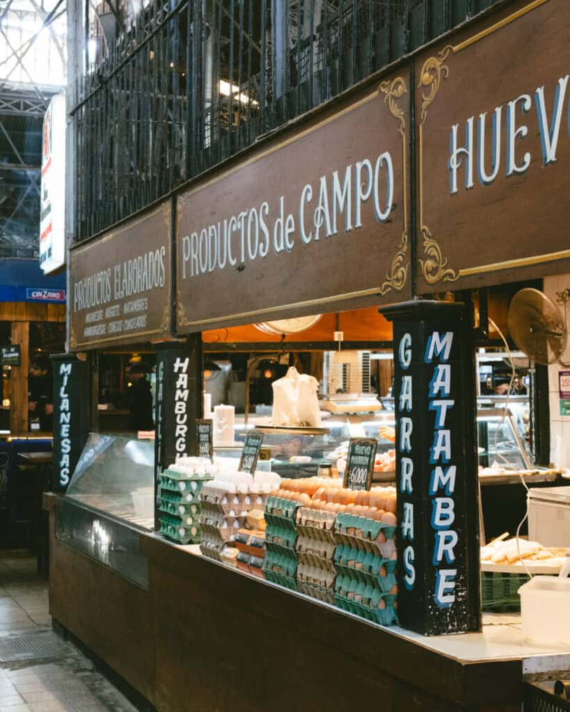 Buenos Aires Food Tour: Sherpa Food Tours in San Telmo 22 Rustic food stall at the market labeled “Productos de Campo” selling eggs, milanesas, matambre, and hamburgers, with stacks of egg cartons arranged neatly on the counter.
