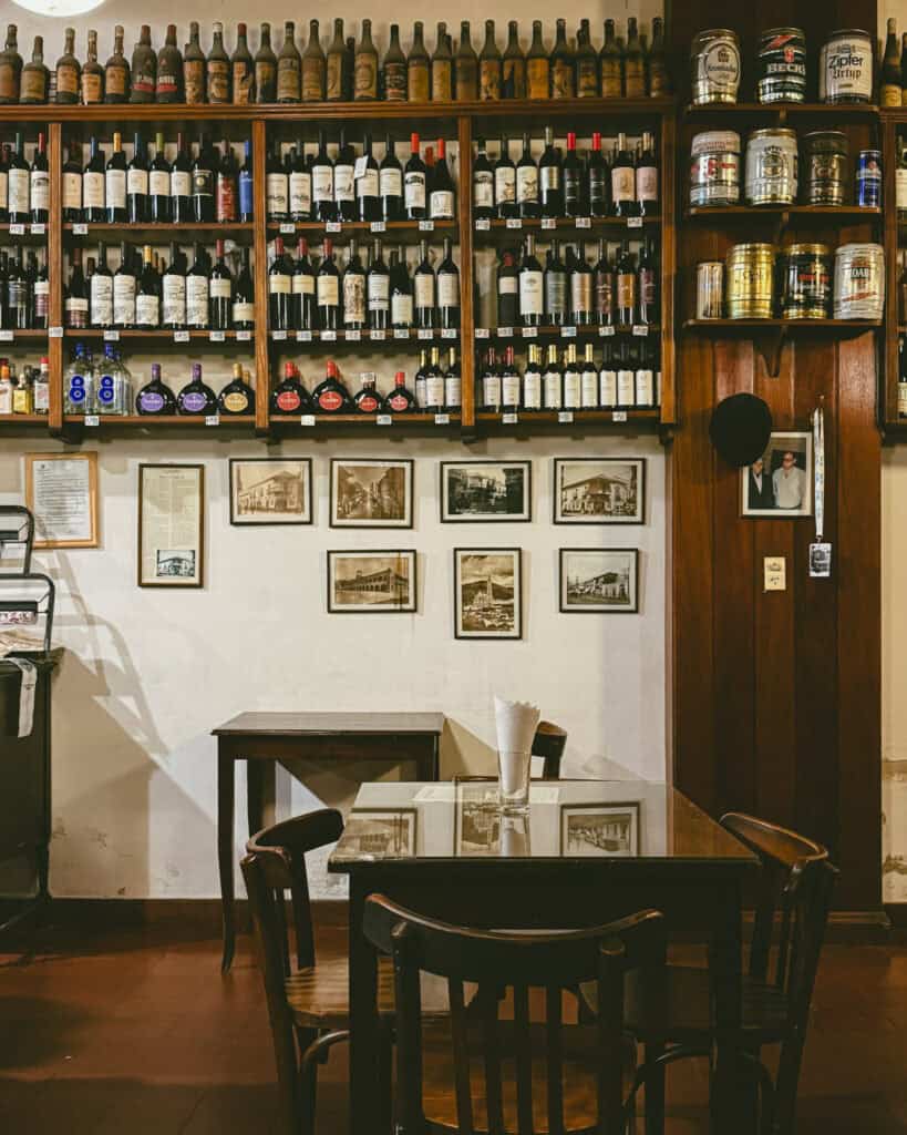 7 - 10 Day Salta Road Trip: The Best of Northwest Argentina 18 Cozy dining area inside Casa Moderna with dark wooden furniture and walls lined with vintage wine bottles, framed photos, and metal beer kegs.