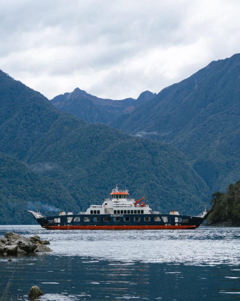 Chaiten, Chile Travel Guide: A Town That Nearly Disappeared 8 Ferry named SOMARCO crossing a lake in Chaitén, surrounded by lush, forested mountains under an overcast sky.
