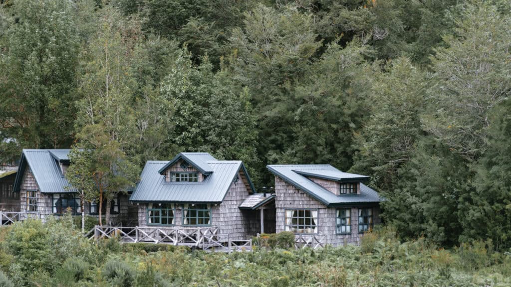 Chaiten, Chile Travel Guide: A Town That Nearly Disappeared 32 Rustic wooden cabins with green tin roofs nestled in thick forest vegetation in Chaitén, Argentina.